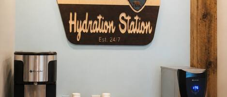 A hydration station with a welcome sign, a water dispenser, and a coffee machine.