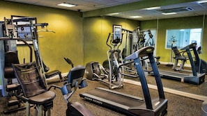 Un gimnasio con diverso equipo de ejercicio, incluyendo cintas de correr y máquinas de pesas.