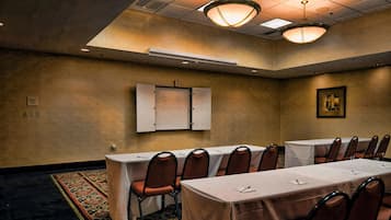 Un salón de conferencias con una mesa larga, sillas y un armario con un letrero.