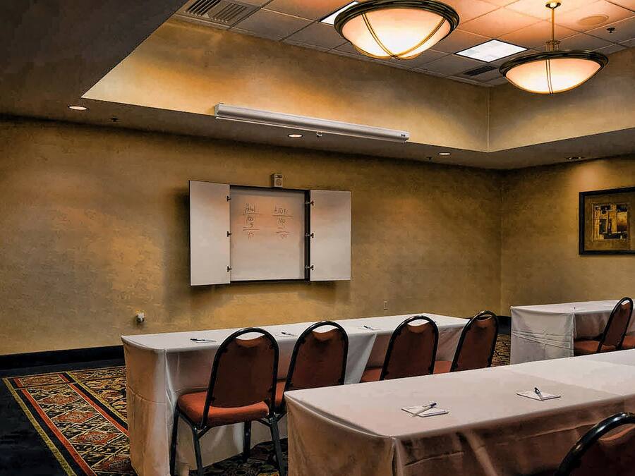 Un salón de conferencias con una mesa larga, sillas y un armario con un letrero.