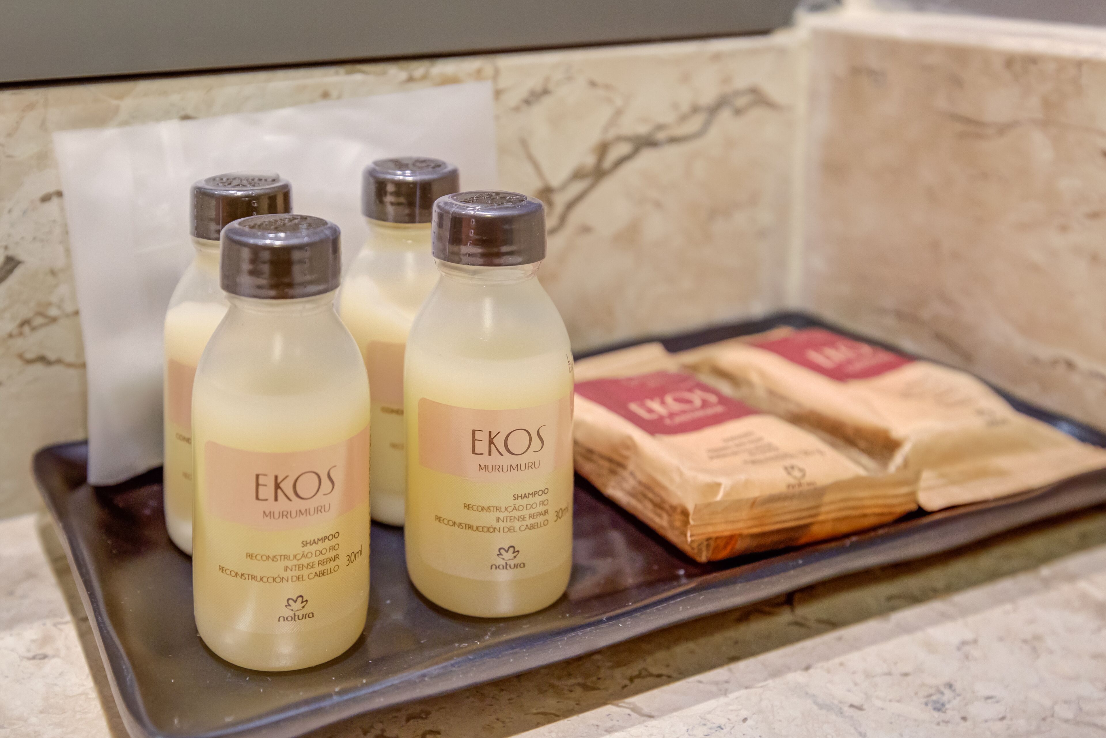 Bottles of EKOS shampoo and soap bars on a tray.