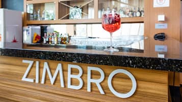Una barra con una copa de vino tinto y el nombre "ZIMBRO" en el panel de madera.