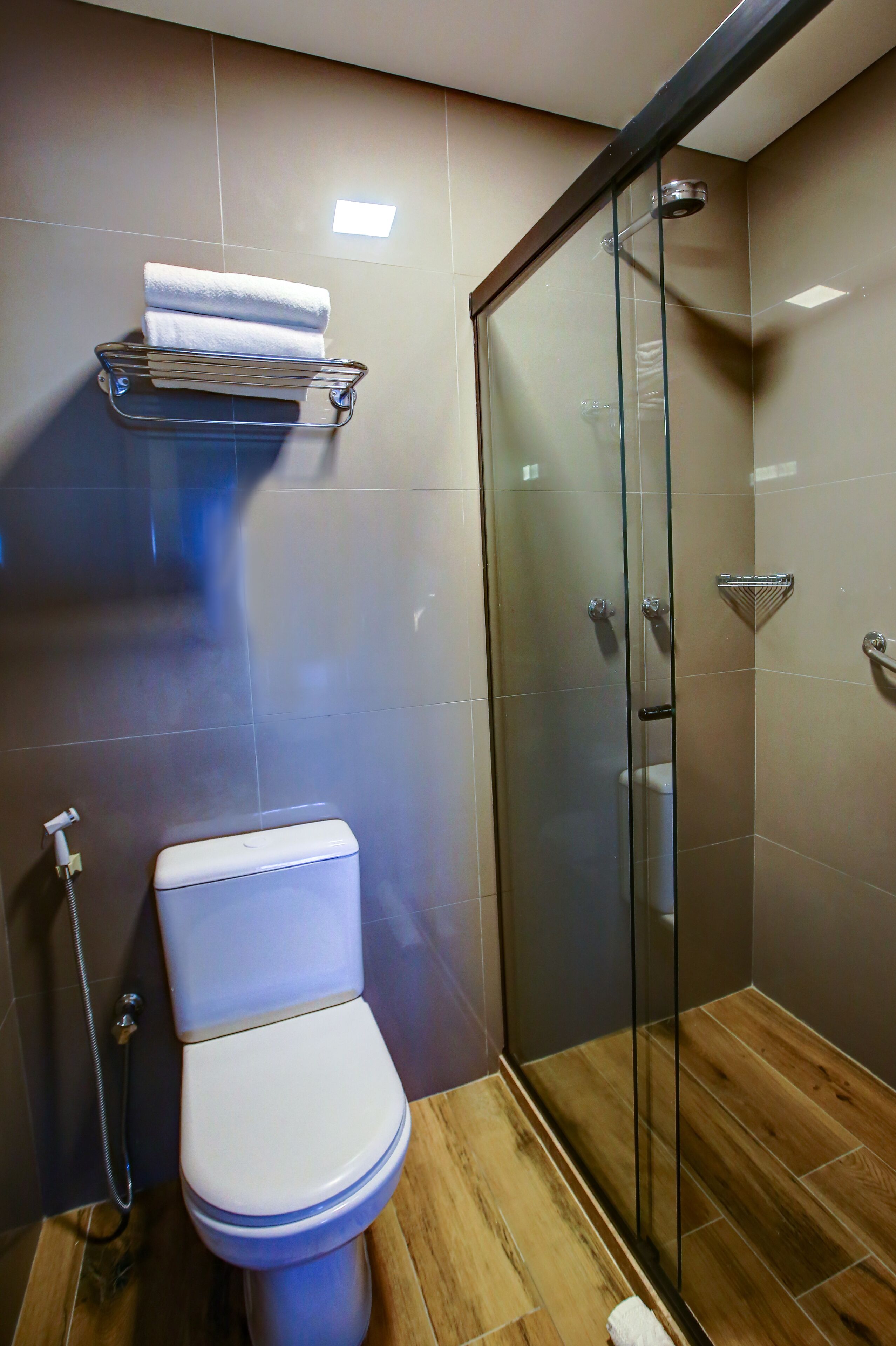 Un baño moderno con inodoro, cabina de ducha de vidrio y un perchero para toallas.