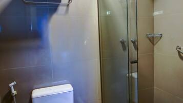 Un baño moderno con inodoro, cabina de ducha de vidrio y un perchero para toallas.