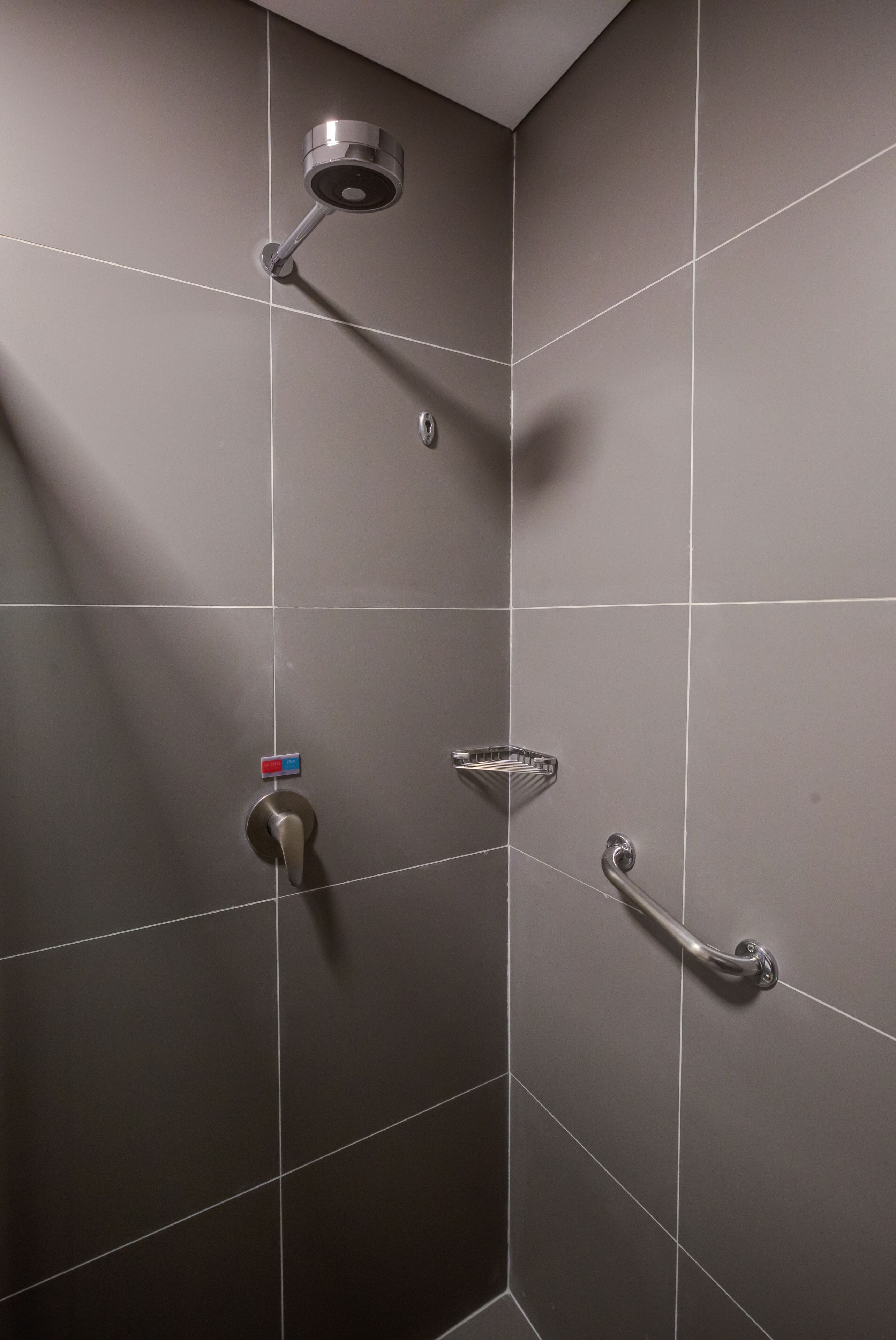A shower area with a handheld showerhead, a handheld showerhead, and a handheld showerhead.