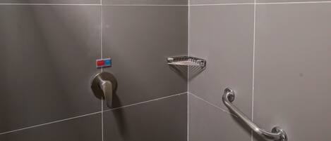 A shower area with a handheld showerhead, a handheld showerhead, and a handheld showerhead.