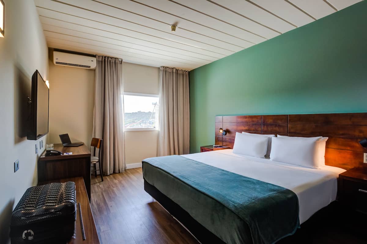 Ein Hotelzimmer mit Bett, Schreibtisch, Stuhl und Klimaanlage.