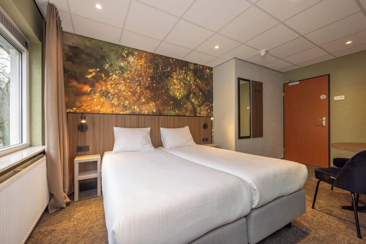 Une chambre d’hôtel avec un grand lit, une petite table de chevet, une chaise, un miroir et une fenêtre avec des rideaux.