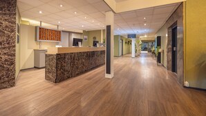A modern hotel lobby with a marble reception desk, a digital screen, and a long corridor with wooden flooring. - Fletcher Hotel-Restaurant Apeldoorn (Apeldoorn)