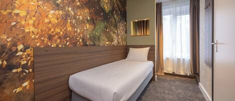 Une chambre d’hôtel avec un lit, une grande fresque murale, une fenêtre avec des rideaux et une porte.
