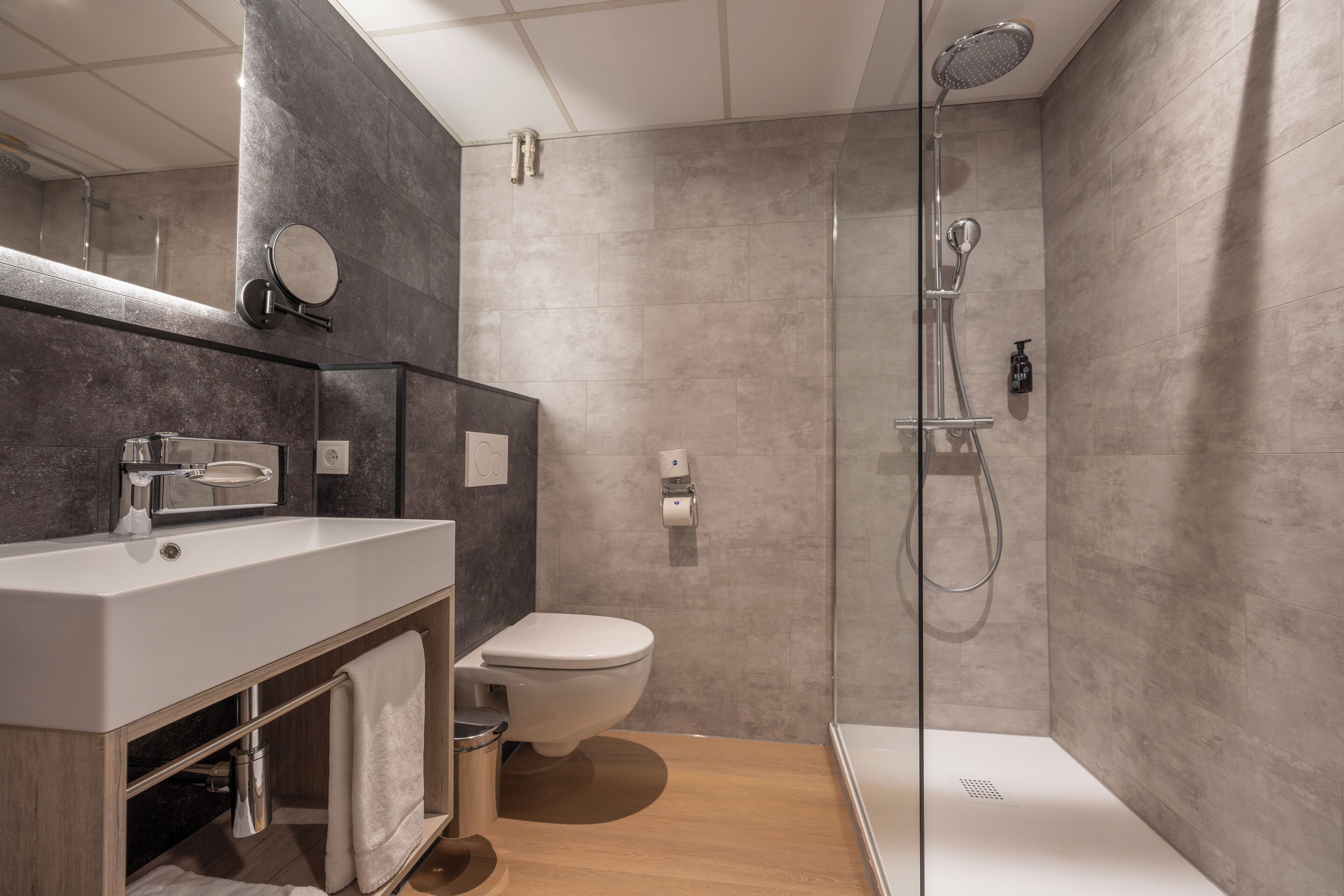 A modern bathroom with a shower, toilet, and sink.