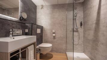 A modern bathroom with a shower, toilet, and sink.