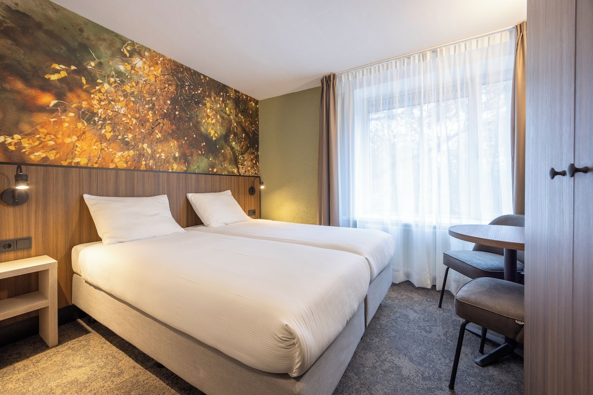 Une chambre d’hôtel avec deux lits, un bureau et une chaise.