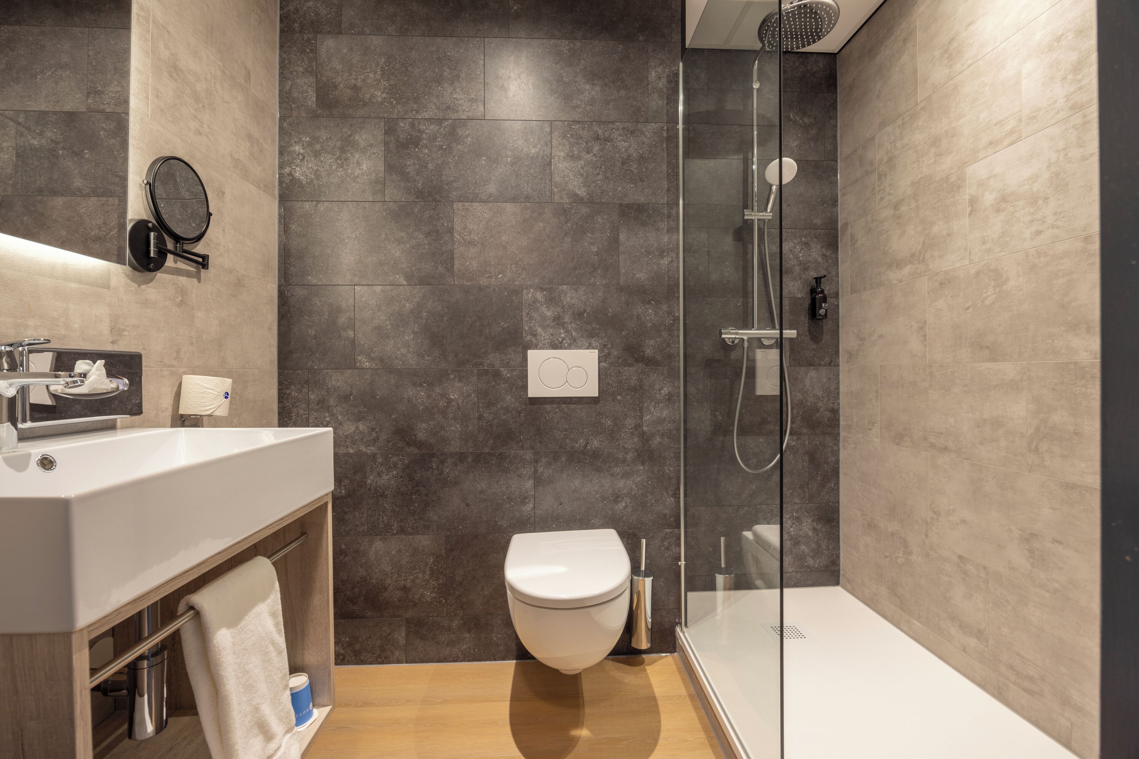 A modern bathroom with a shower, toilet, and sink.