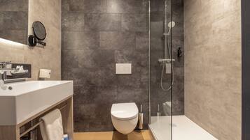 A modern bathroom with a shower, toilet, and sink.