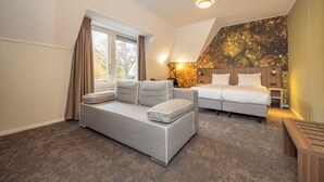 A modern bedroom with a grey sofa, a bed, and a large window with curtains. - Fletcher Hotel-Restaurant Apeldoorn (Apeldoorn)