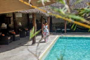 A poolside area with lounge chairs and a thatched roof structure.
