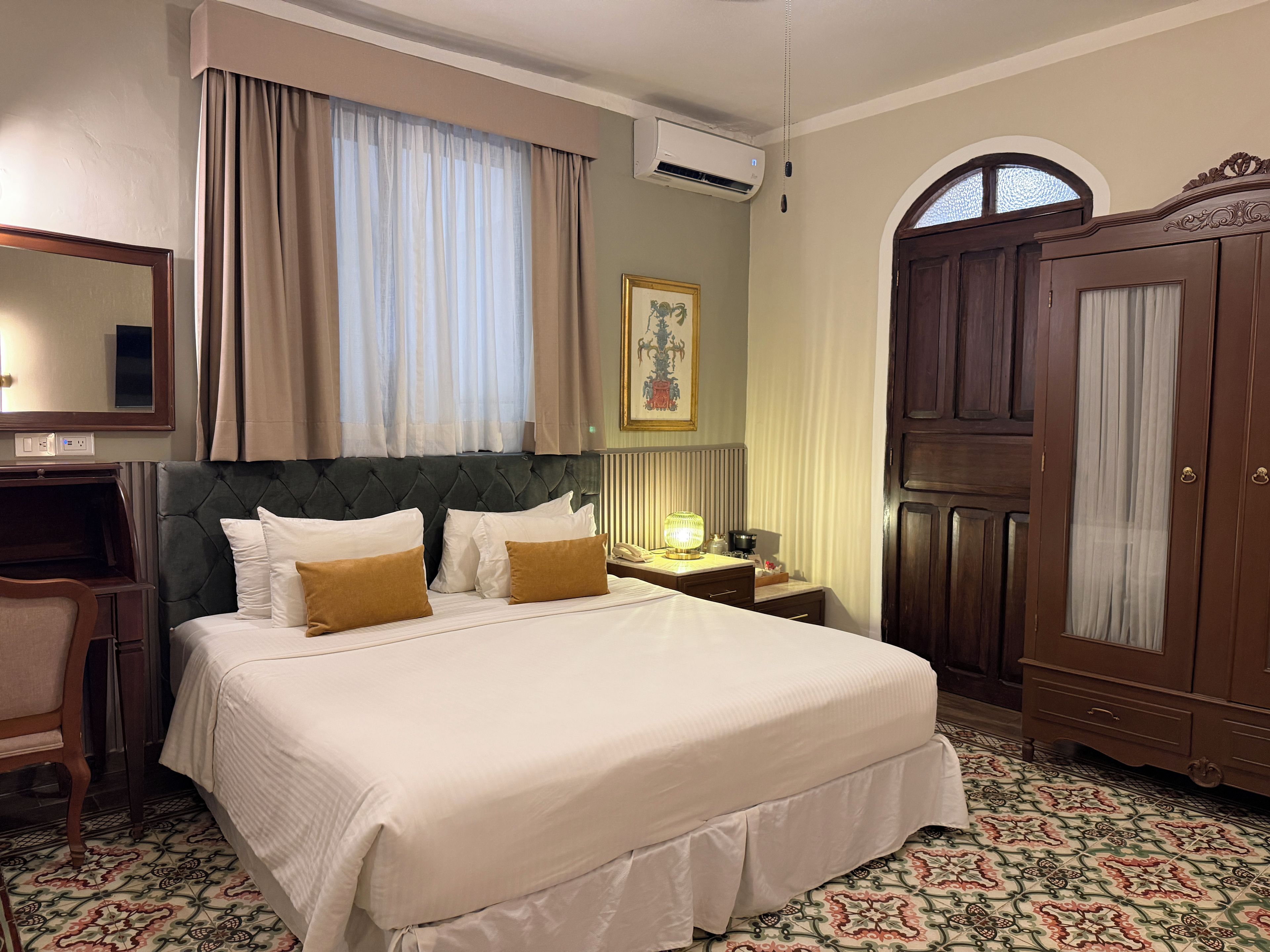 Habitación de hotel con una cama grande, un escritorio, un armario y una ventana con cortinas.