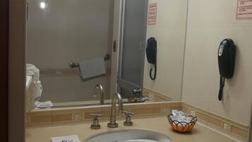 Un baño de hotel con lavamanos, espejo, toallero y teléfono.