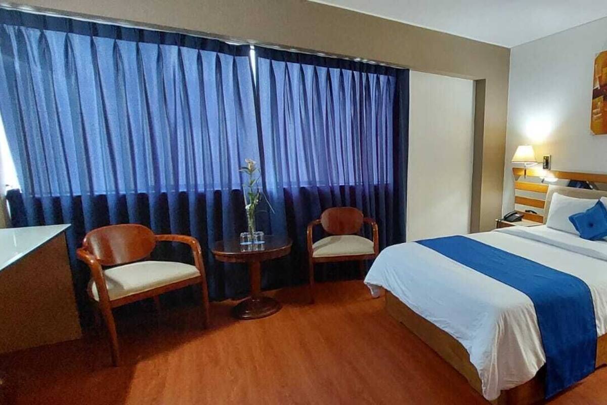 Una camera d'albergo con un letto, due sedie, un tavolino e una scrivania.