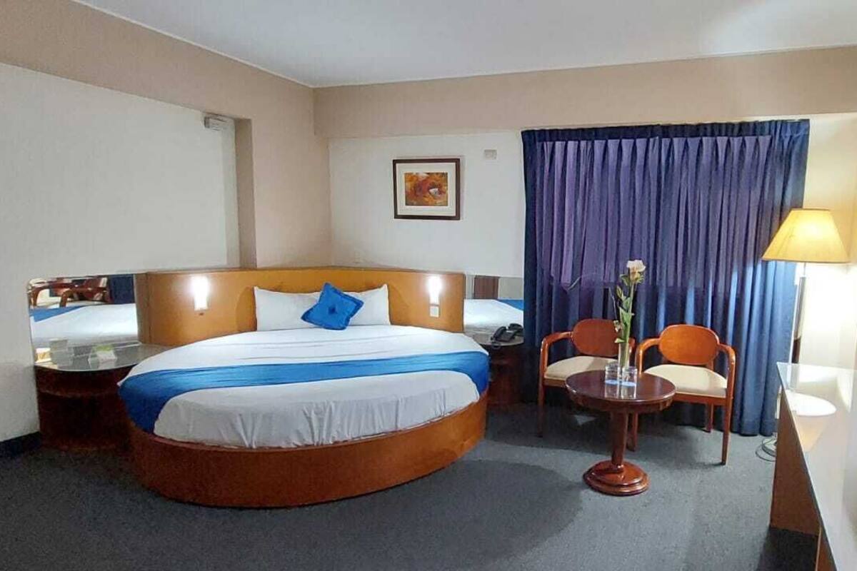 Una camera d'albergo con un letto grande, una scrivania, una sedia, una lampada e un televisore.