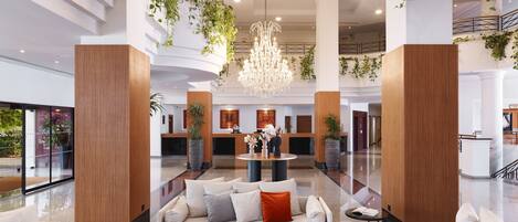 Um hall amplo com balcão de recepção, área de estar e um candelabro.
