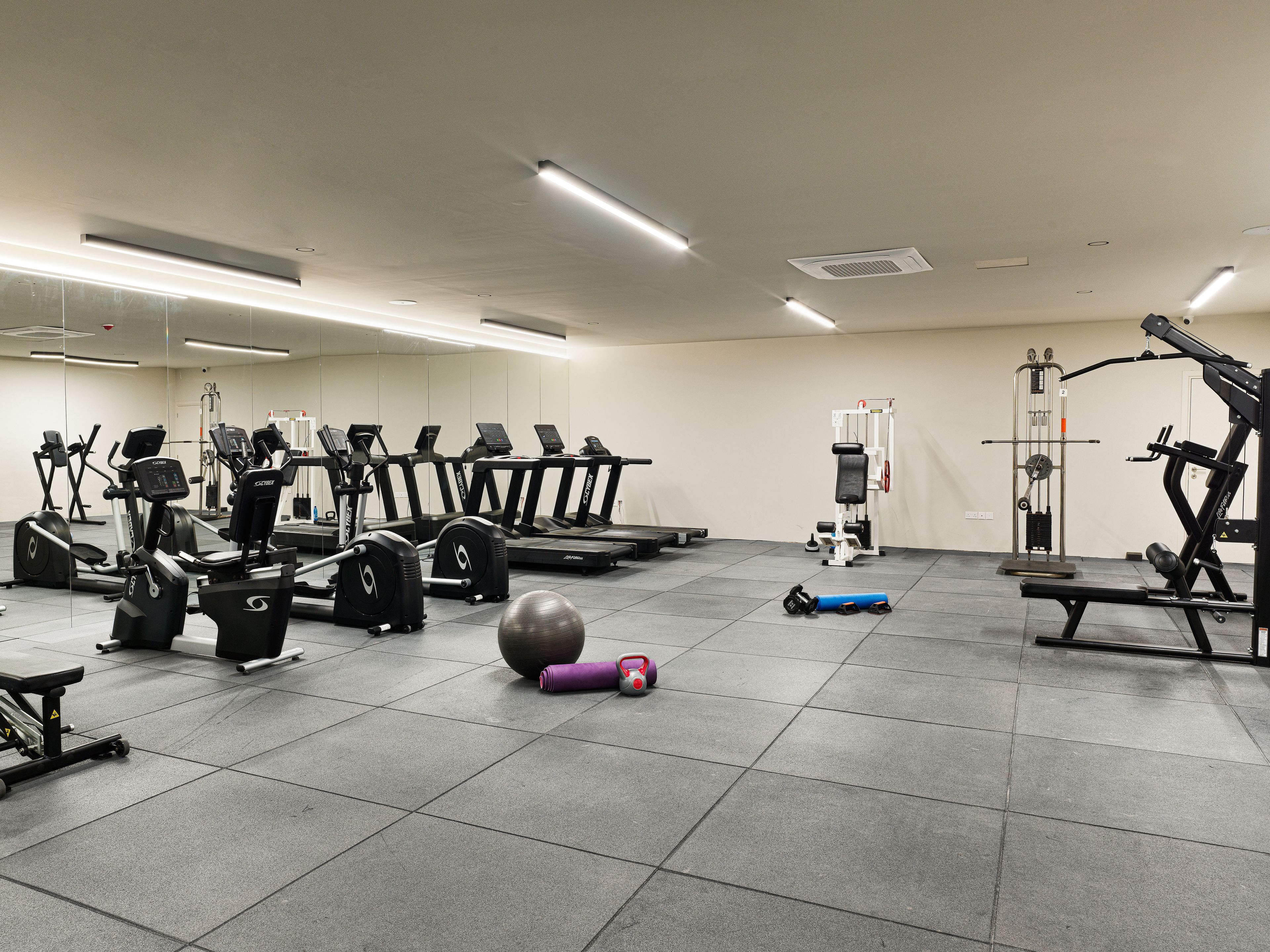 A gym with treadmills, weight machines, and exercise balls.