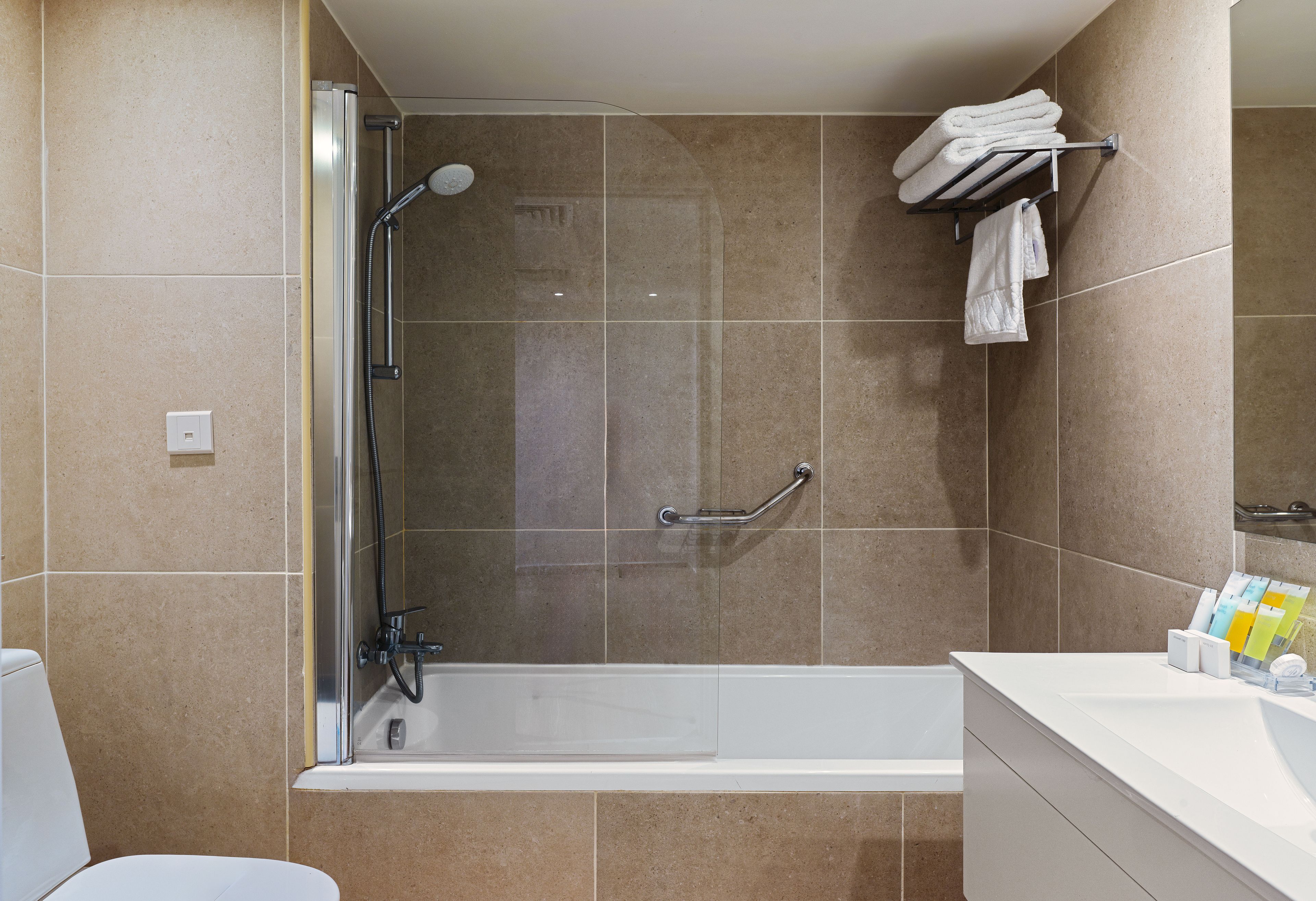 Un bagno moderno con doccia vetrata, una vasca da bagno bianca e un portasciugamani a parete.