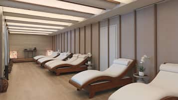 A spa room with multiple sun loungers, a wooden floor, and a ceiling with skylights.