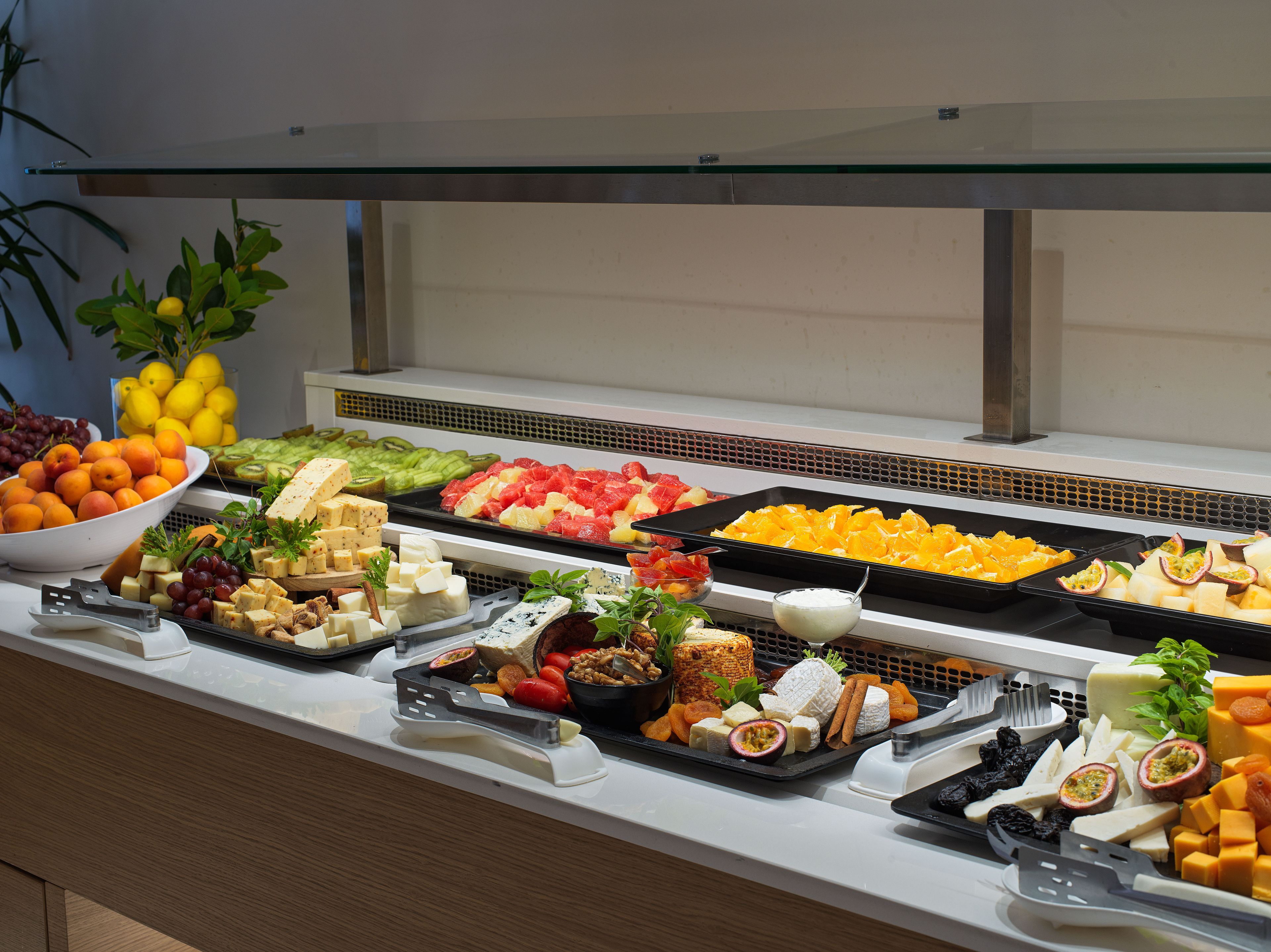 A buffet with various cheeses, fruits, and vegetables.