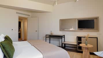 Una habitación de hotel con una cama, un escritorio, un televisor y una mesita con un jarrón.