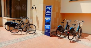 A bike rental station with bicycles parked in front of a building with a signboard advertising bike rentals. - Venus Beach Hotel (Paphos)