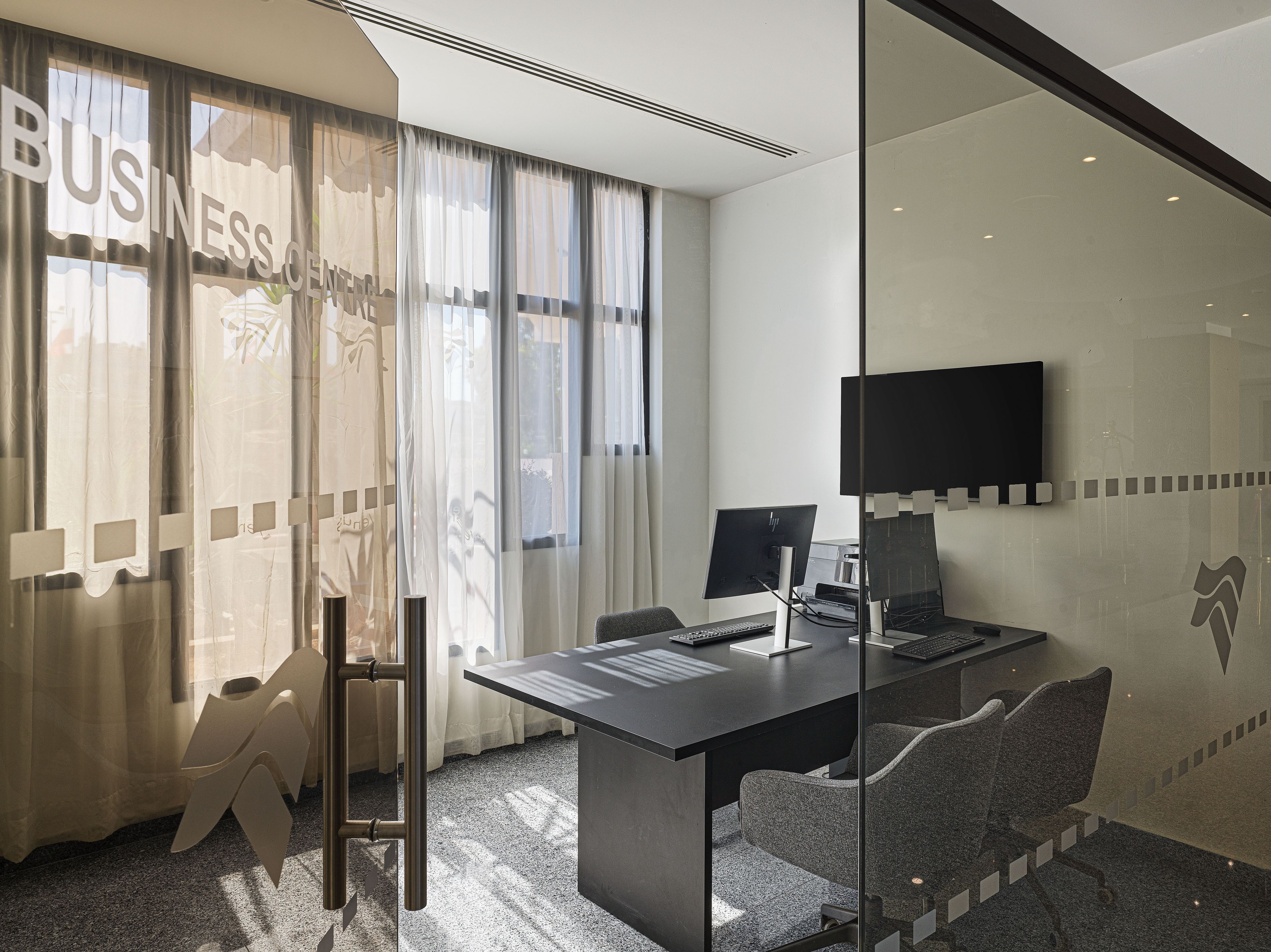Un espacio de oficina moderno con un panel de vidrio, un escritorio con computadora y una silla.