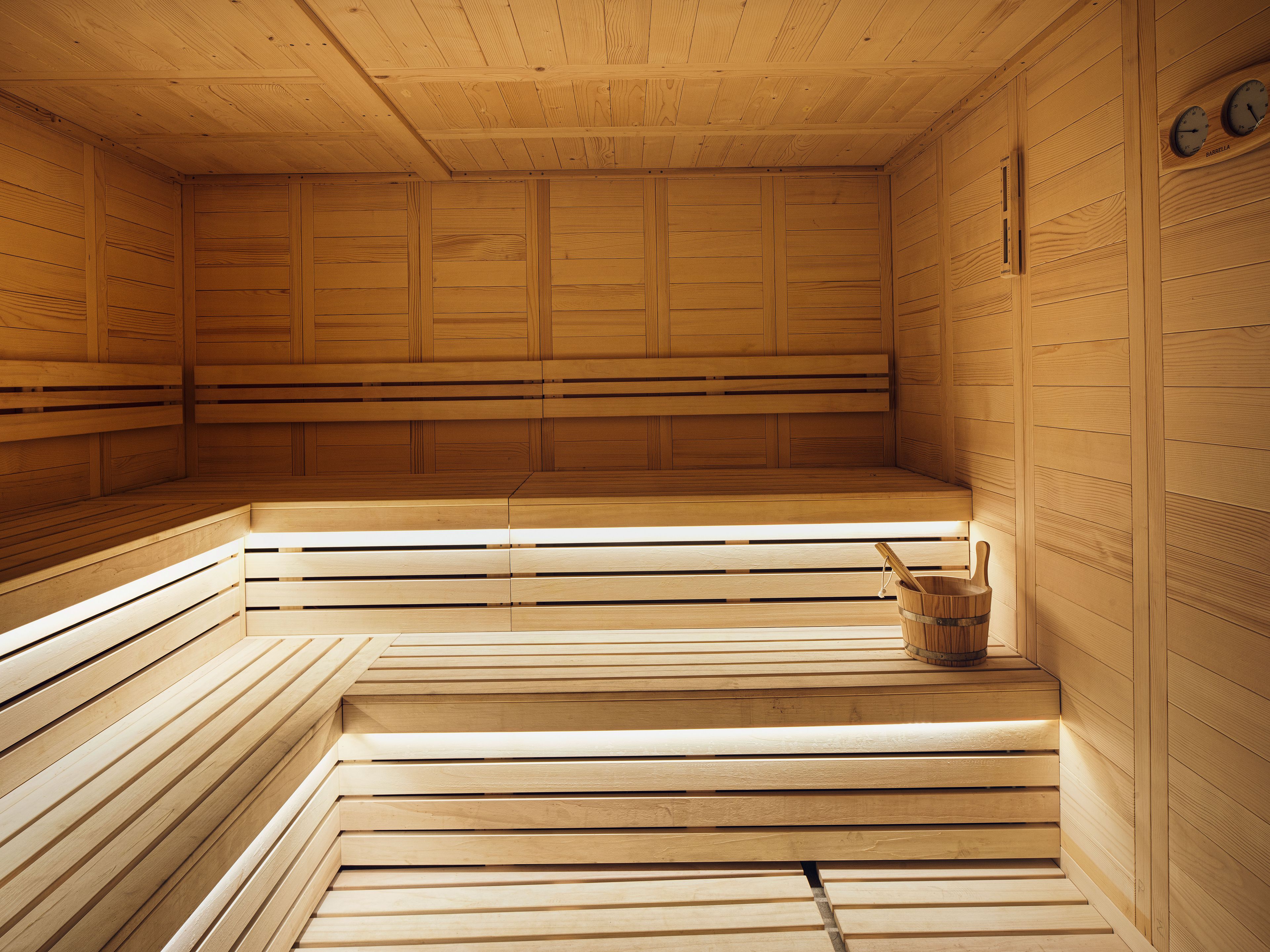 A sauna with wooden benches and a bucket.