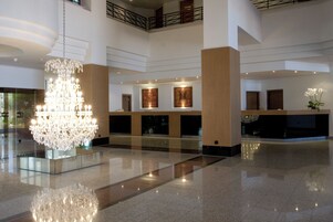 Un vestíbulo espacioso con una gran lámpara de candelabro, un mostrador de recepción y un techo alto.
