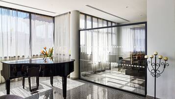 A modern interior with a piano, a glass partition, and a candelabra.
