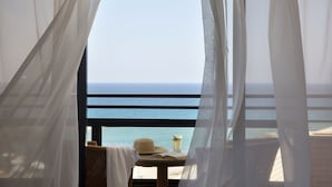 A balcony with a view of the ocean, a table with a hat and a book, and sheer curtains. - Venus Beach Hotel (Paphos)