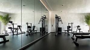 A gym with exercise equipment, a large mirror, and potted plants. - Venus Beach Hotel (Paphos)