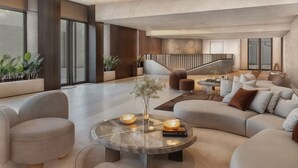 A spacious living area with a round coffee table, sofas, and a staircase leading to an upper level.