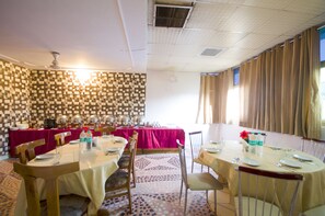 Un comedor con mesas redondas, sillas y un papel tapiz estampado.
