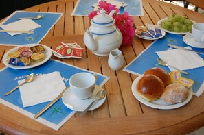 Een gedekte tafel met een theepot, kopjes, borden met gebak en een schaal druiven.