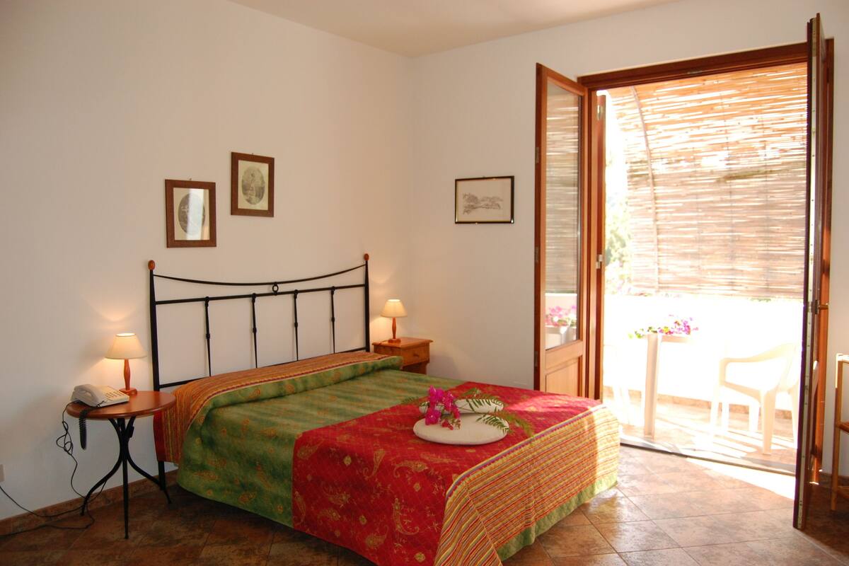 A bedroom with a bed, bedside tables, and a door leading to a balcony.