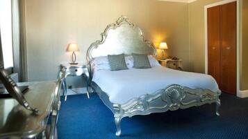 A hotel room with a large bed, two bedside tables, and a wardrobe.