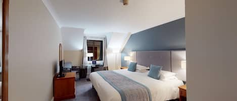 A hotel room with a large bed, bedside tables, a desk, and a mirror.