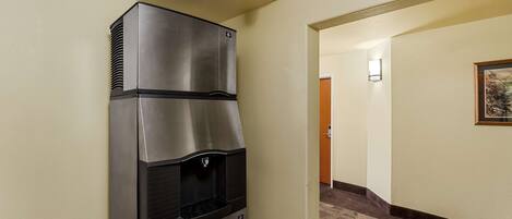 A hallway with a stainless steel refrigerator and a water dispenser, a framed picture on the wall, and a carpeted floor.