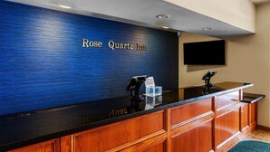 A reception desk with a blue textured wall and the name "Rose Quartz Inn" in gold lettering. There are two card readers and a glass display case. - Best Western Rose Quartz Inn (Chester)