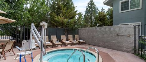 A backyard with a swimming pool, lounge chairs, and a stone wall.