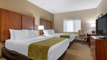 A hotel room with two beds, a desk, a chair, and a television.