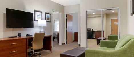 A hotel room with a desk, chair, television, and a green sofa.