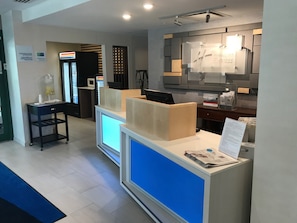 A reception desk with a blue accent, a microwave, and a vending machine in the background. - Holiday Inn Express Hotel & Suites Rochester - Victor by IHG (Victor)